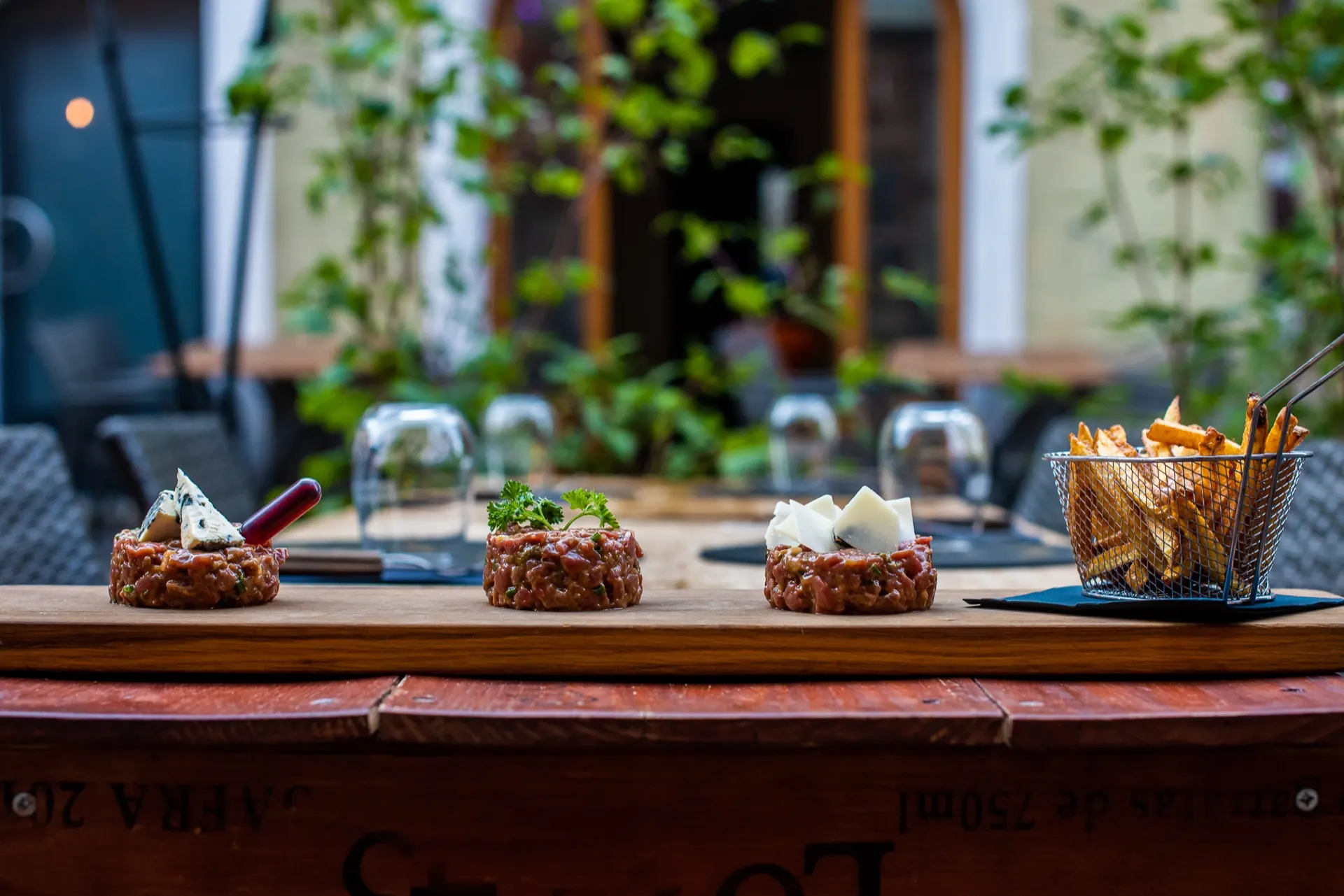 Assortiment de trois tartares de bœuf sur planche, servis dans la cour du Café National