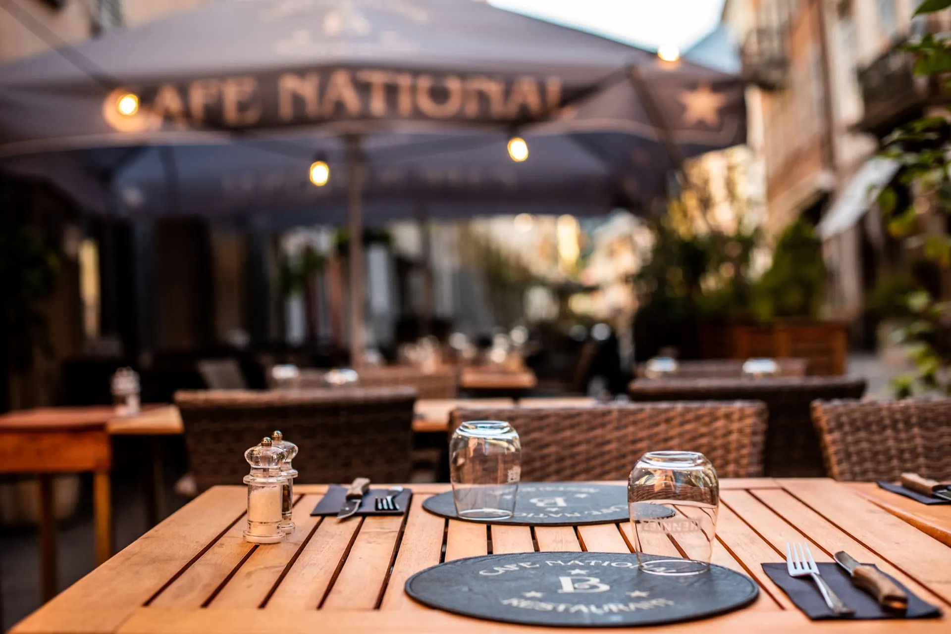 Restauration — Table dressée en terrasse du Café National à la lumière dorée de fin de journée